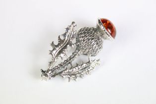 A silver thistle pendant brooch set with amber