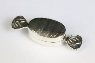 A silver pill box in the form of a sweet