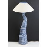 Ceramic pottery lamp base of spiralling shape having a blue ground with raised white detailing and