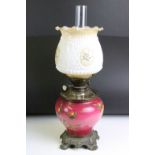 An antique oil lamp having floral decoration to base and opaque shade and scrolled feet. Measures