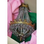 Brass chandelier of crown form, with hanging crystal droplets, decorated with strings of faceted