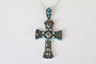 A silver pendant cross set with turquoise and ruby cabochons.