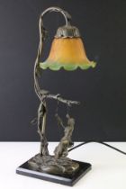 Art Nouveau style bronze table lamp in the form of a woman on a swing, with a green & orange mottled