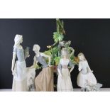 Two large Lladro figurines in the form of a girl holding a flower beside a bench and a veiled woman,