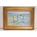 A gilt framed impressionist oil painting, mother and children paddling at the seaside, 26 x 41cm