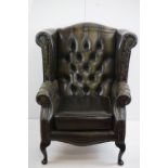 Green Leather Button Back Wing Back Armchair in the George III manner, raised on four cabriole legs,