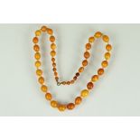 Early 20th century Butterscotch amber bead necklace, forty-two oval and round graduated beads, the
