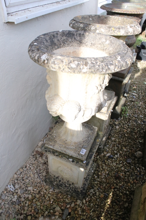 Pair of reconstituted stone garden urns of campana form, with relief facial mask decoration and