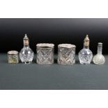 A collection of six cut glass vanity jars and bottles with silver lids and stoppers.
