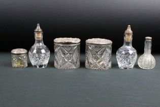 A collection of six cut glass vanity jars and bottles with silver lids and stoppers.