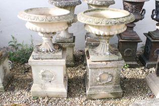 Pair of reconstituted stone garden urns, the bowls of shallow form, with ovolu-moulded rims and