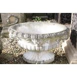 Reconstituted stone garden planter of oval form, with relief lion masks, raised on a fluted oval