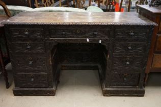 Victorian Dark Oak Twin Pedestal Desk with heavy foliate carving and an arrangement of nine drawers,