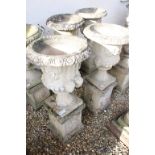 Pair of reconstituted stone garden urns of campana form, with relief facial mask decoration and