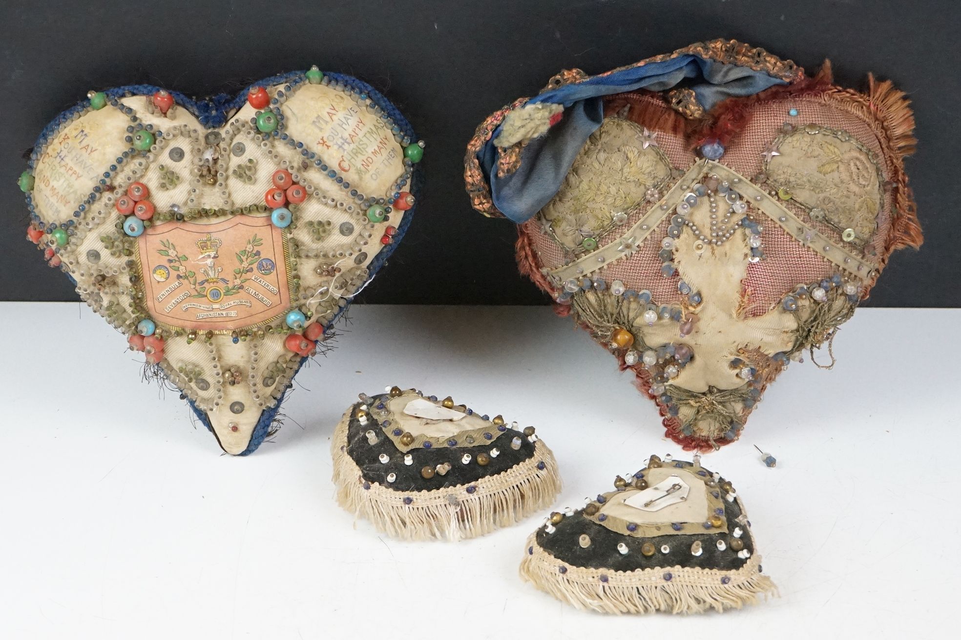 Four 19th Century Edwardian pin cushions to include one commemorative example stitched with a