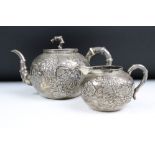 An antique Chinese silver teapot cast with cherry blossom decoration and bamboo style handles and