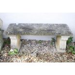 Reconstituted stone garden bench / seat of rectangular form, raised on two feet scrolled feet. (