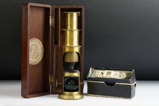 An early 20th century students microscope contained within a fitted wooden case with Cambridge