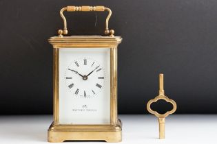 A brass cased carriage clock with bevelled glass panels, white enamel dial with retailers mark '