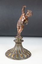 Antique cast bronze putti figurine depicting a classical putti with symbols raised on a fluted