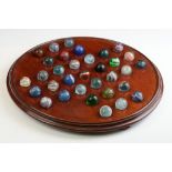 An early 20th century wooden solitaire board complete with marbles to include some early examples.