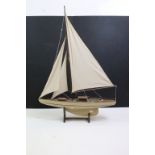 Wooden model of a yacht, with mast, sails & rigging, with wooden stand. (Measures approx 87cm high)