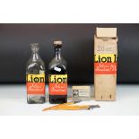A Lion brand bottle of ink together with an empty bottle and dip pens.