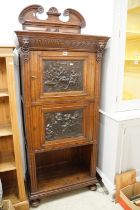 19th century Continental Carved Oak Cupboard, the pair of doors inset with bronzed panels with scnes