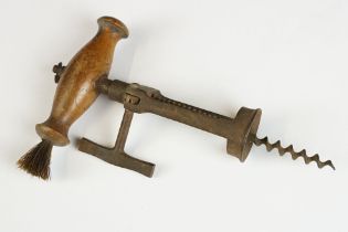 An antique corkscrew with wooden handle and brush.
