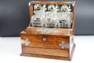 Late Victorian oak games tantalus with silver plated mounts, housing three cut glass decanters &