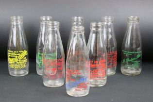 Set of eight vintage glass milk bottles complete with advertising to the sides.