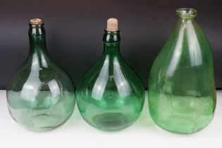 Three green glass bottles / carboys to include a pair of bulbous form (with stoppers) and a
