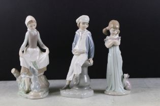 Three Lladro figurines to include a boy holding a model ship, lady with a hare and a girl with a