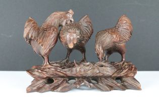 A hand carved wooden oriental ornament of three chickens / cocks on raised base.