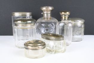 A collection of antique glass jars and scent bottles with hallmarked silver tops and collars.