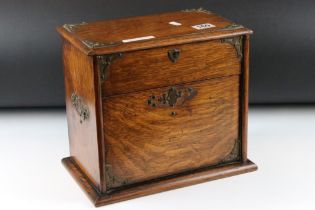 Edwardian oak stationery cabinet, the raising of the lid causing the lower compartment to open,