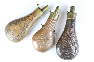 A group of three antique copper powder flasks with brass fittings.