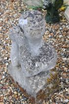 Reconstituted stone garden statue in the form of a man with hands clasped, raised on a stone plinth.