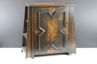 Early-to-mid 20th century oak smokers cabinet of tapering form, the door opening to two drawers and