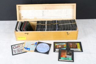 A collection of approx 50 glass magic lantern slides contained within a wooden case to include