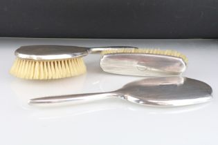 Silver backed dressing table brush set, comprising hand brush, hand mirror and clothes brush, reeded