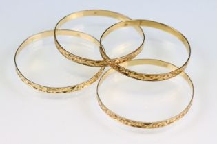 Four 18ct yellow gold bangles, foliate scroll decoration in relief, width approx 5mm, interior