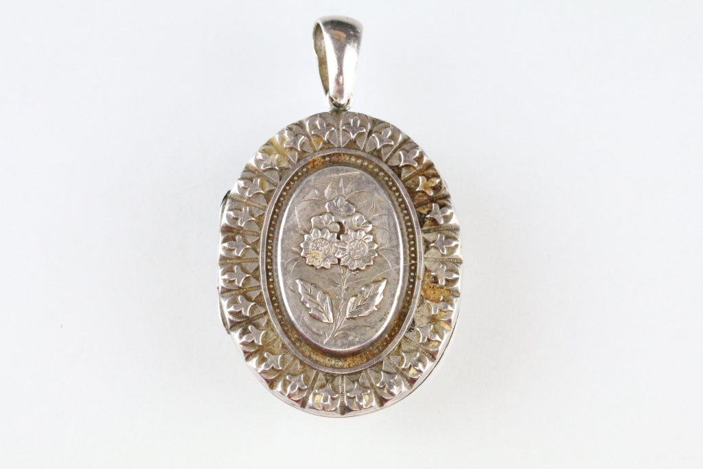 Victorian silver locket pendant, the raised oval centre with cast flower decoration, stylised