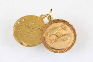 18ct gold pendant with two fish in relief, diameter approx 2cm; together with a yellow metal