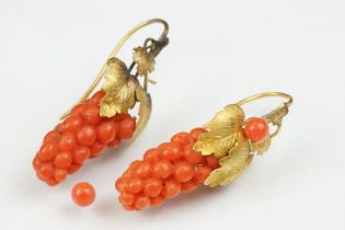 Pair of 19th century carved coral yellow metal earrings, the coral carved as grapes, cast vine