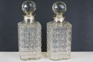 A pair of cut glass drinks decanters with fully hallmarked sterling silver collars.