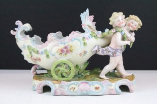 20th Century German porcelain figural vase featuring two putti pulling a floral moulded cart.