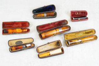 A collection of seven amber cheroot holders to include some with silver mounts, all contained within