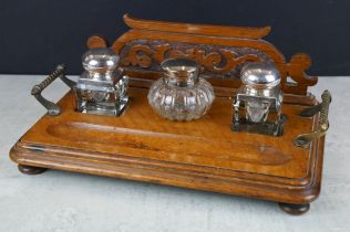 Early 20th century oak triple inkwell desk stand, the glass inkwells with silver plated covers, with