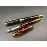 Two JINHAO fountain pens on black mottled one red mottled